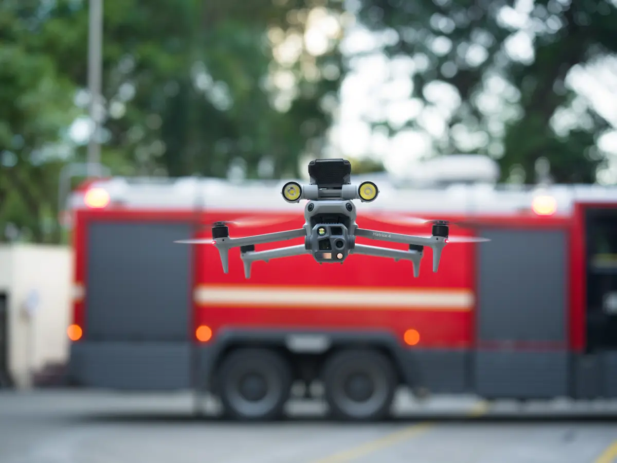 Dron DJI Matrice 4 z reflektorem w zawisie przed wozem strażackim podczas działań